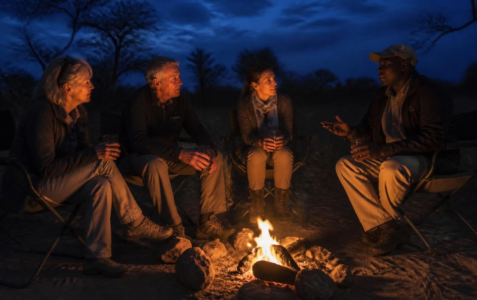 Guests around a campfire during blue hour before a stargazing session
