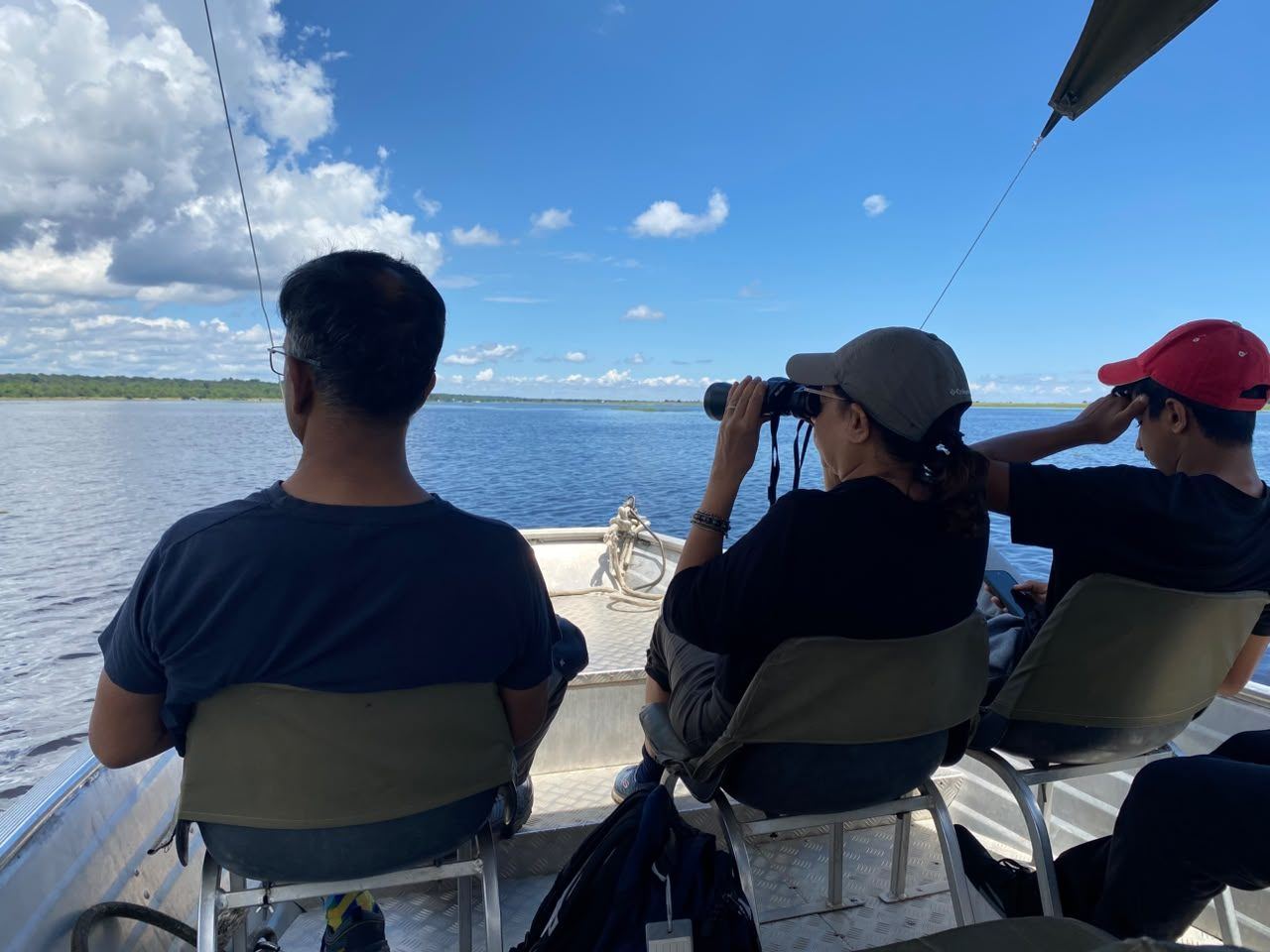 Family watching wildlife across the Chobe River from an open boat