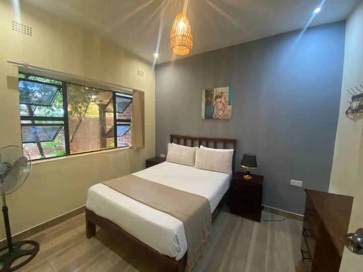 Granadilla Cottage bedroom with a queen bed, crisp linen and a garden window