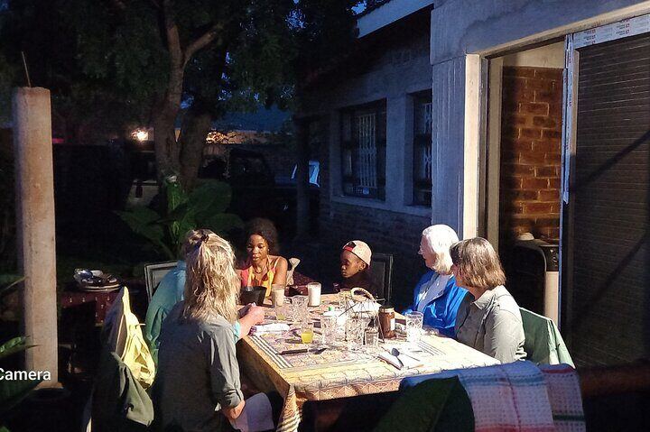 Guests at an outdoor dinner table lit by warm lamplight at night