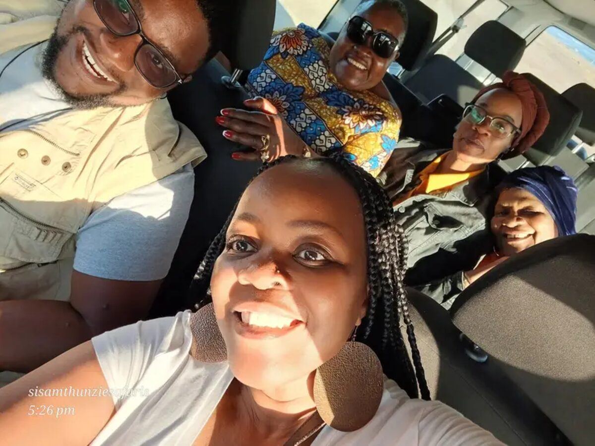 Guests in an open safari vehicle wearing hats and sunglasses on a game drive