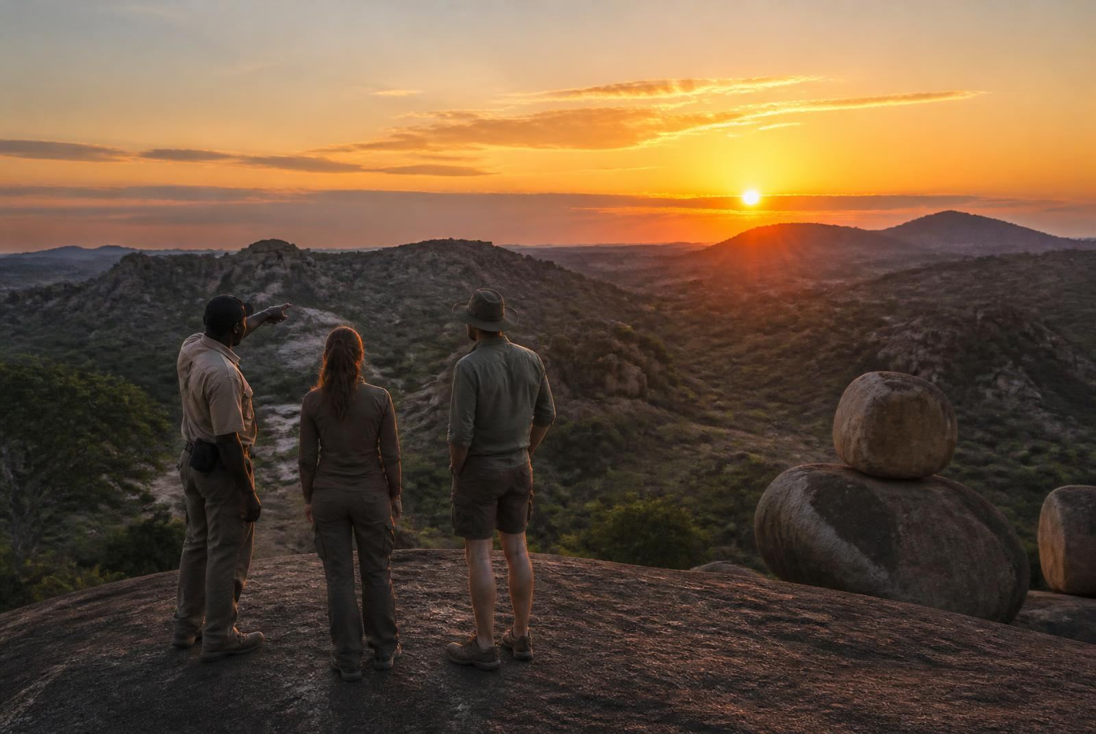 Guide and guests watching sunrise from a granite dome in the Matobo Hills