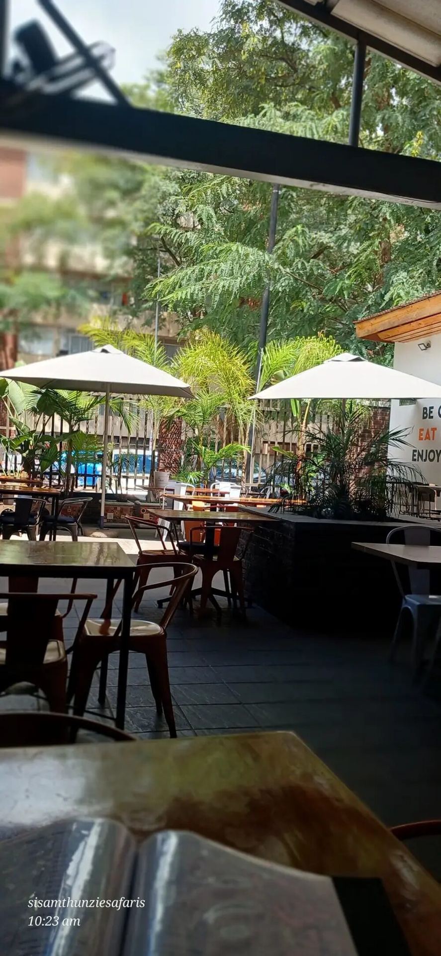 Cafe terrace in Victoria Falls with white umbrellas and wooden tables in morning light