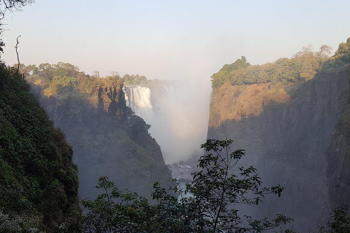 Victoria Falls plunging into the misty main gorge between sunlit cliffs